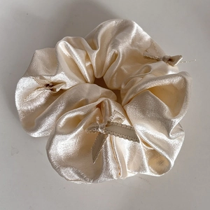 Detail of champagne satin scrunchie with delicate ribbon bows and pleated texture