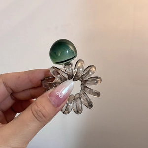 Transparent grey spiral telephone wire hair tie with a textured green resin bead accent