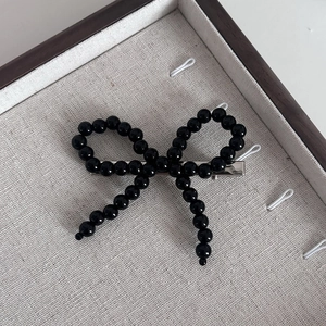 Pince à cheveux élégante avec nœud en perles noires sur support en lin de luxe