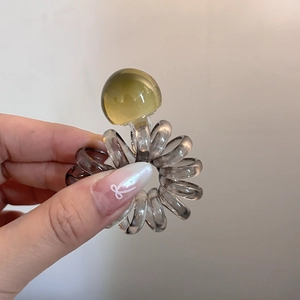 Detail of spiral telephone wire hair tie with large olive green transparent bead decoration