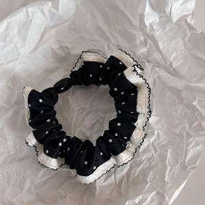 Polka dot hair scrunchie with white ruffled edges on artistic white background
