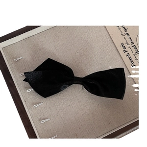 Sweet black asymmetric bow hair clip with textured matte finish on a display board