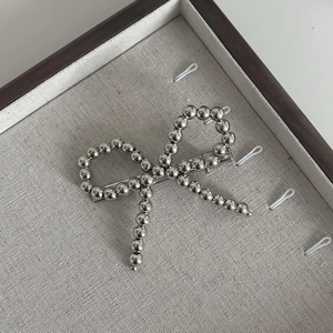 Barrette à cheveux avec nœud en perles argentées et structure métallique élégante