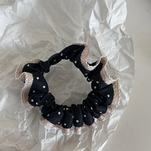 Black polka dot scrunchie with beige lace trim and wave edge on white paper