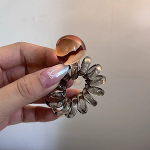 Close-up of translucent amber bead on dark grey spiral telephone wire hair tie