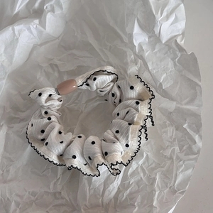 Detailed view of oversized polka dot hair scrunchie with ruffle edges and plastic buckle