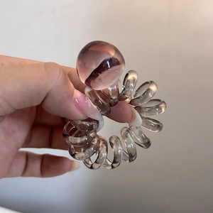 Close-up of a translucent smoky grey spiral hair tie with a smooth resin bead detail