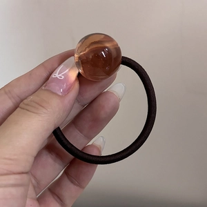 Dettaglio ravvicinato di un elastico per capelli marrone con perla in resina ambra traslucida