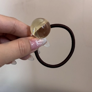 Dettaglio di un elastico per capelli con una sfera decorativa in resina ambrata trasparente