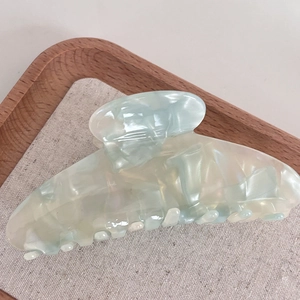 Elegant large marble light blue acetate hair claw clip for women on a wooden tray