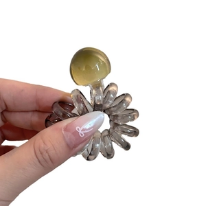 Spiral telephone cord hair tie in smoky gray with a ginger yellow decorative bead accent