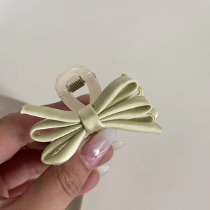 Macro shot of light green satin bow hair claw clip with transparent resin grip