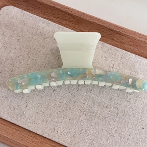 Macro detail of acetate shark hair claw showing green marble texture and pearly shell flakes