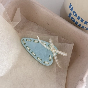 Close-up of mint green acetate hair clip with marble texture and beige ribbon bow detail