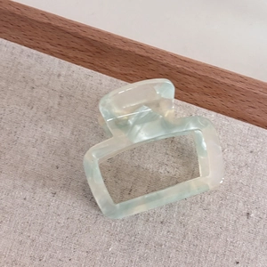 Macro view of light green marble acetate hair claw clip with rectangle hollow design