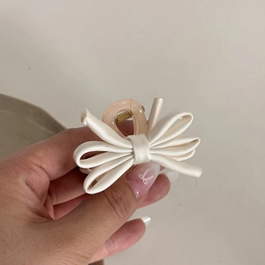 Detailed close-up of a ballet style cream silk bow hair claw clip with resin teeth