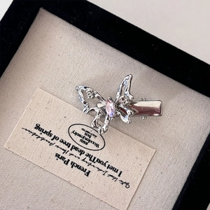 Eleganter silberner Schmetterling-Haarclip mit Strass und rosa Stein auf rustikalem Grund