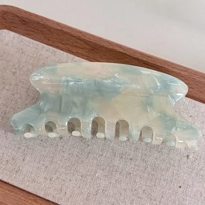 Macro shot of large acetate claw clip with marble texture in light green and ivory hues