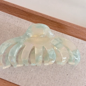 Macro detail of large light green acetate hair claw clip with elegant marble texture pattern