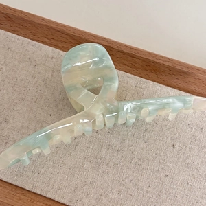 Detail shot of a large acetate shark hair clip with light green marble texture