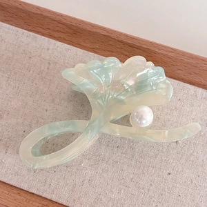Macro shot of green acetate shark hair clip with ginkgo leaf design and white pearl detail