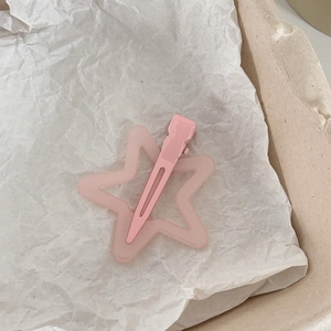 Détail d'une pince à cheveux rose bonbon en forme d'étoile avec une finition mate et un clip