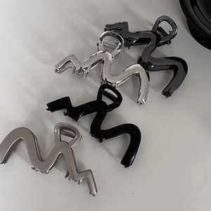 Detailed view of four large wavy metal hair claws in silver, grey, black, and gold colors