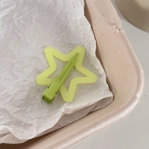 Détail d'une pince à cheveux étoile vert clair avec texture mate sur papier blanc