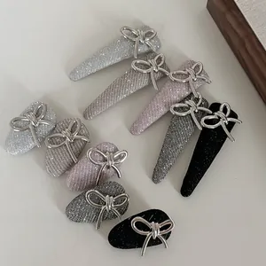 Macro detail of glitter fabric hair clips with silver metallic bow accents and BB duckbill grip