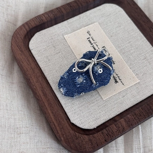 Close-up of strawberry denim hair clip with silver bow and sequins on a tray