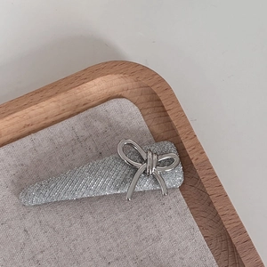 Elegant silver glitter hair clip with bowknot detail on wooden display tray