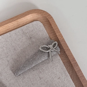 Detailed view of silver glitter hair clip with metallic bow on a rustic fabric background
