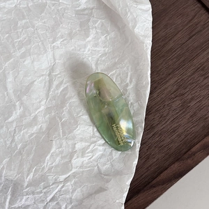 Detail of green marble acetate hair clip with gold France Handmade lettering and metal clip