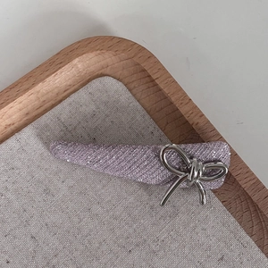Close-up of glitter lavender hair clip with a silver metal bow detail on a tray