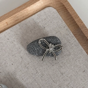 Macro detail of a silver glitter bow hair clip with textured metallic craftsmanship