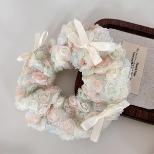Close-up of pastel mesh rose flowers and satin bow hair scrunchie on a wood tray