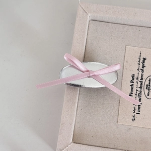 Gros plan d'une barrette argentée avec un nœud en ruban rose sur toile beige élégante