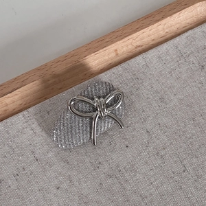 Macro detail of silver glitter hair clip featuring a polished metallic bow on linen background