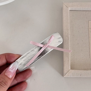 Barrette en cuir argenté avec nœud en ruban rose sur fond esthétique neutre