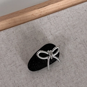 Detailed view of a silver glitter bow hair clip with a sleek metallic finish and dark base