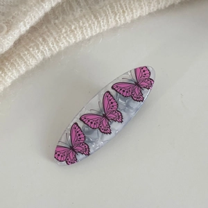 Elegante molletta per capelli in marmo grigio con farfalle rosa su sfondo di tessuto bianco