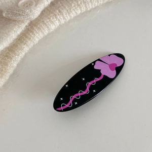 Dettaglio molletta ovale in acrilico nero con motivi floreali viola e linee rosa curve