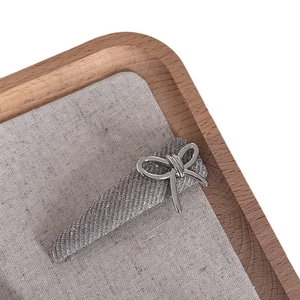 Sparkling silver bow hair clip with fine glitter texture on a wooden tray