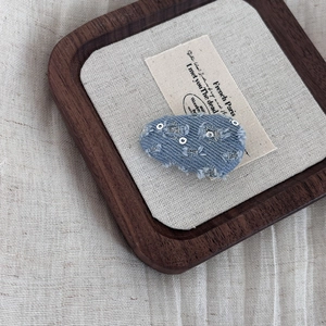 Denim bow hair clip with silver stars and frayed edges on a vintage canvas background