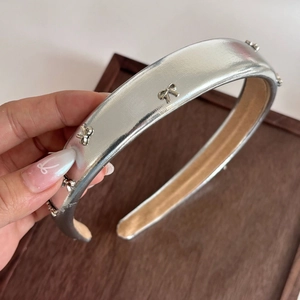 Dettaglio di un cerchietto in ecopelle argento con piccoli fiocchi metallici decorativi
