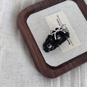 Close-up of tweed hair clip with silver bow detail and sparkling sequins on wood tray