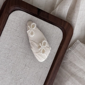 Elegant cream bow hair clip with pearl embroidery on a vintage style fabric base
