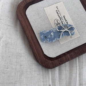 Close-up of denim bow hair clip with silver sequins and metallic bow detail