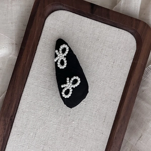 Detailed close-up of handmade black fabric bow hair clips with delicate white pearl accents