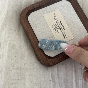 Detail of light blue denim hair clip with silver sequins and rustic frayed edges